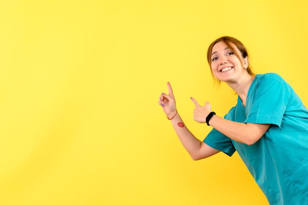 Vue de face femme médecin souriant sur l'espace jaune