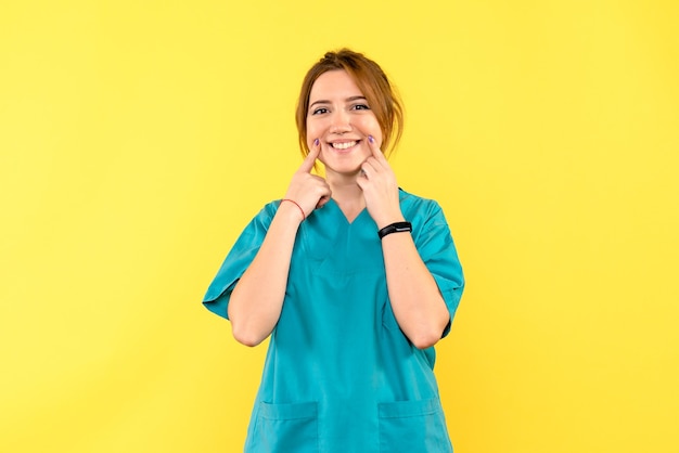 Vue de face femme médecin souriant sur l'espace jaune