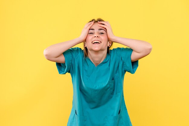 Vue de face femme médecin souriant sur fond jaune médical émotion santé de l'hôpital