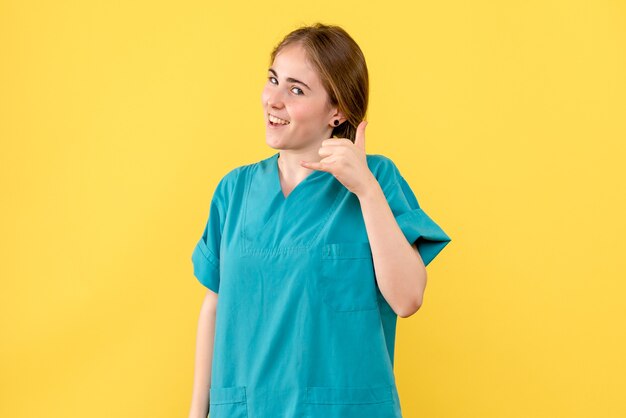 Vue de face femme médecin souriant sur fond jaune médical émotions santé hôpital