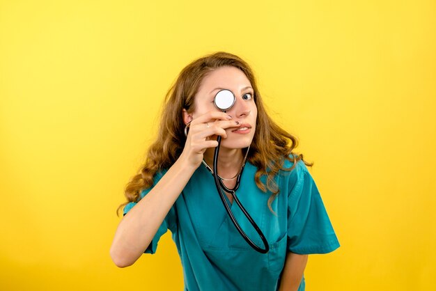 Vue de face femme médecin avec stéthoscope sur espace jaune