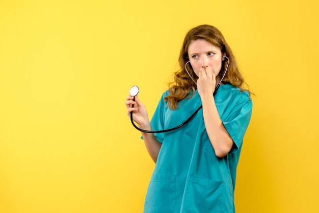 Vue de face femme médecin avec stéthoscope sur espace jaune