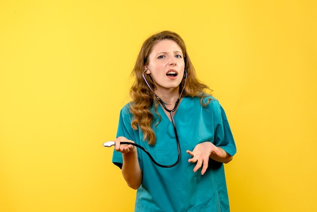 Vue de face femme médecin avec stéthoscope sur espace jaune