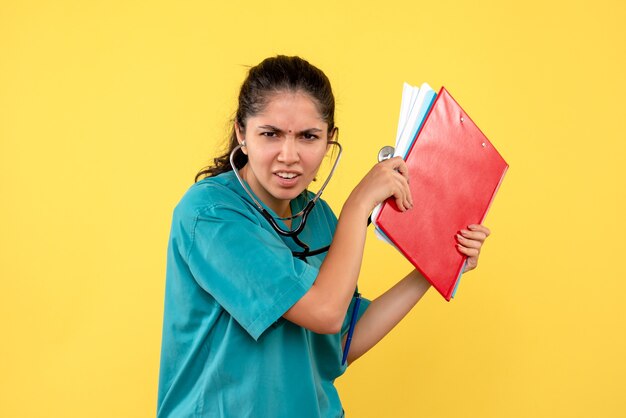 Vue de face femme médecin avec stéthoscope tenant des dossiers debout