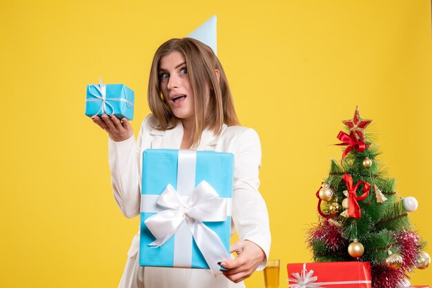 Vue de face femme médecin tenant des cadeaux de Noël