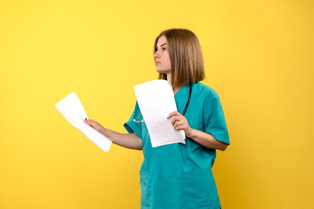 Vue de face femme médecin tenant des documents sur l'espace jaune