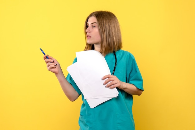 Vue de face femme médecin tenant des documents sur la maladie de l'hôpital médical plancher jaune