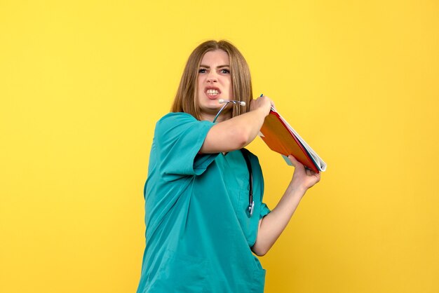 Vue de face femme médecin tenant des documents sur le sol jaune analyse médicale de l'hôpital