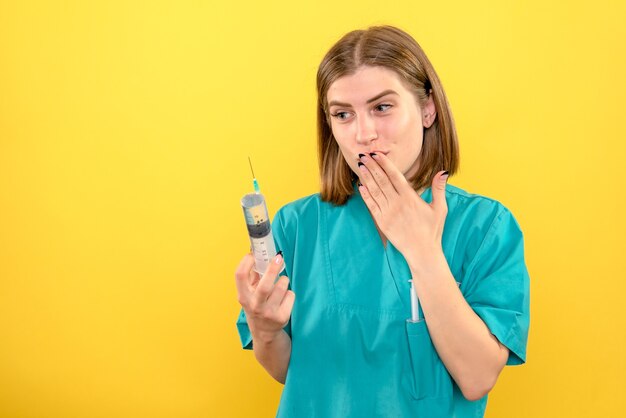 Vue de face femme médecin tenant une énorme injection sur l'espace jaune