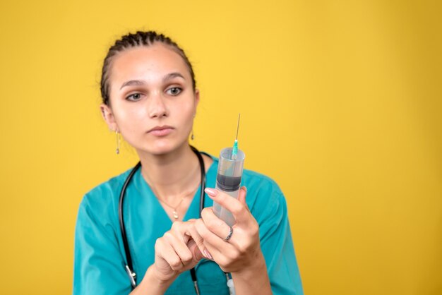 Vue de face femme médecin tenant une énorme injection, infirmière médicale de l'hôpital de virus médical covid-19