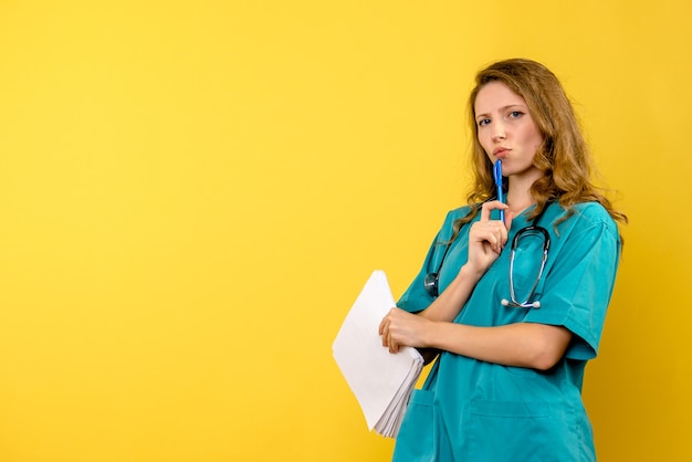 Photo gratuite vue de face femme médecin tenant des fichiers sur l'espace jaune