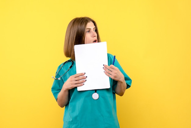 Vue de face femme médecin tenant des fichiers sur le sol jaune couleur de l'hôpital médical