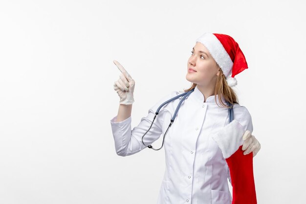 Vue de face d'une femme médecin tenant une grosse chaussette de vacances sur un mur blanc