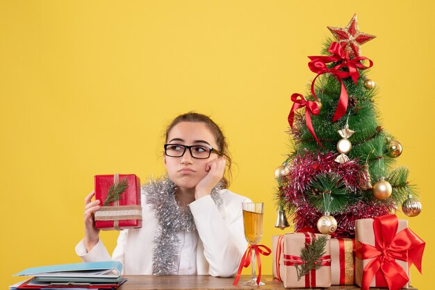 Vue de face femme médecin tenant peu de cadeau avec visage ennuyé