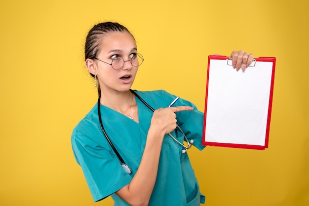 Vue de face femme médecin tenant presse-papiers médical et stylo, couleur infirmière hôpital émotion covid-19 santé