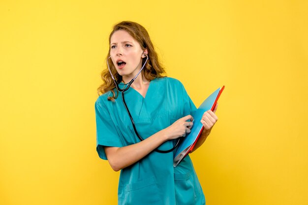 Vue de face femme médecin tenant stéthoscope sur espace jaune