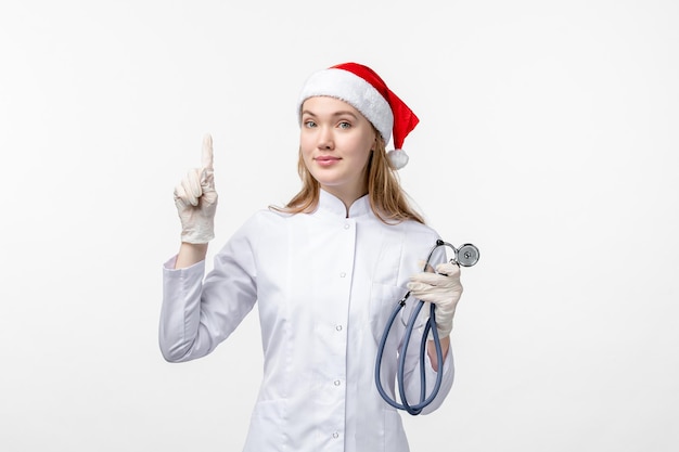 Vue de face d'une femme médecin tenant un stéthoscope sur un mur blanc