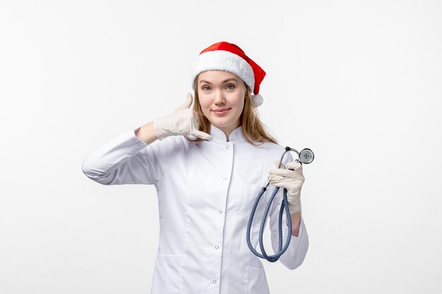 Vue de face d'une femme médecin tenant un stéthoscope sur un mur blanc