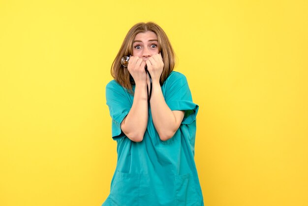 Vue de face femme médecin tenant tonomètre sur espace jaune