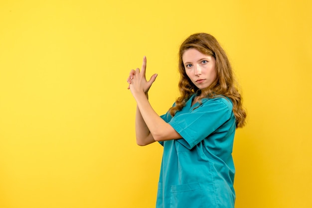 Vue de face femme médecin en tenue de pistolet pose sur l'espace jaune