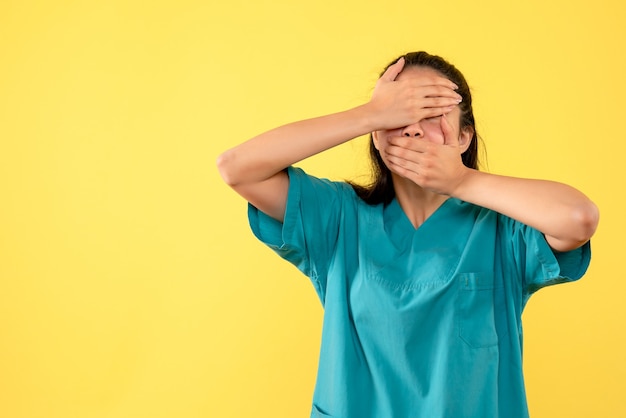 Vue de face femme médecin en uniforme couvrant ses yeux et sa bouche debout