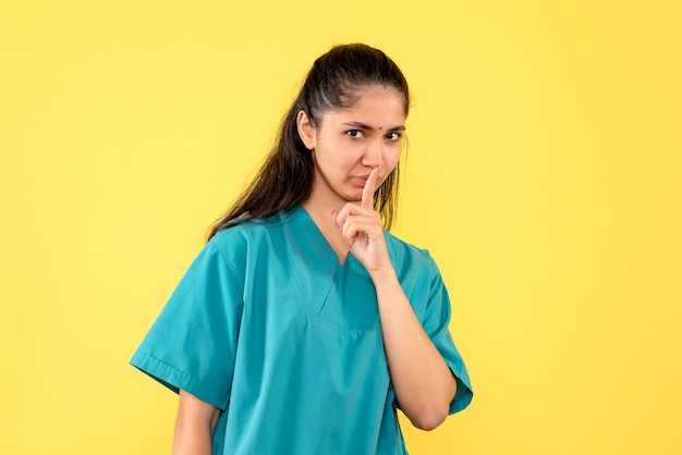 Vue de face femme médecin en uniforme faisant signe chut debout