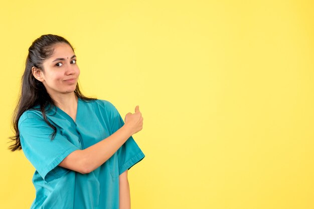 Vue de face femme médecin en uniforme pointant vers l'arrière