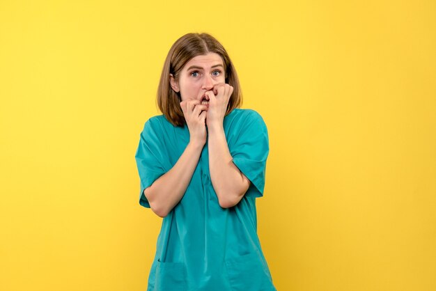 Vue de face de femme médecin avec visage effrayé sur mur jaune