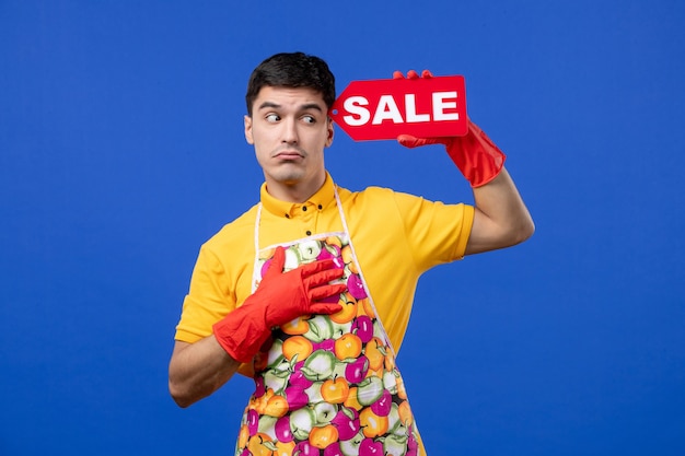Vue de face femme de ménage confuse en t-shirt jaune tenant une pancarte de vente sur un espace bleu