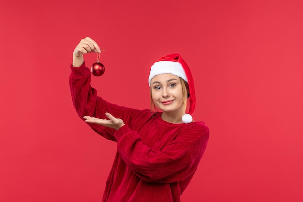 Vue de face femme ordinaire tenant des jouets de noël sur un bureau rouge vacances de noël rouge