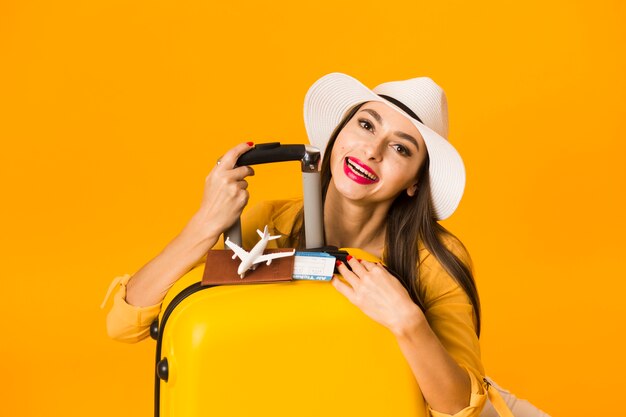 Vue de face de femme posant avec des bagages et des essentiels de voyage