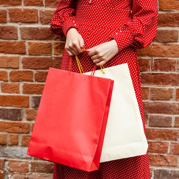 Vue de face de la femme posant à l'extérieur tout en tenant des sacs à provisions