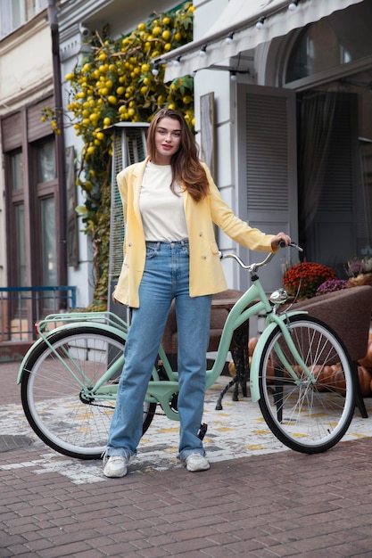 Vue de face de la femme posant avec son vélo dans la ville