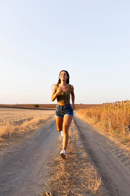 Vue de face de la femme qui court sur la route dans la nature avec espace copie