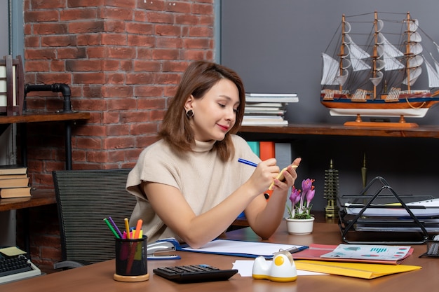 Vue de face d'une femme satisfaite prenant des notes travaillant au bureau