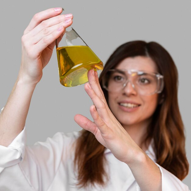 Vue de face de la femme scientifique avec tube à essai et lunettes de sécurité