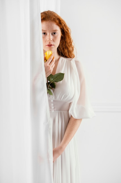 Vue de face d'une femme séduisante posant avec une fleur de printemps