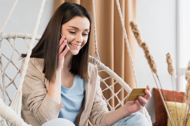 Vue de face de femme sur smartphone et tenant une carte de crédit