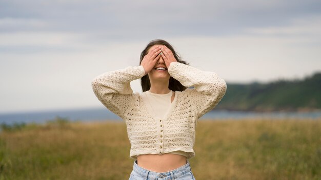 Vue de face femme souriante couvrant ses yeux