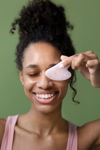 Vue de face femme souriante avec gua sha