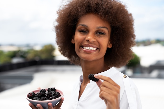 Vue de face femme souriante mangeant des mûres