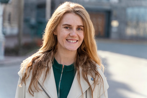 Vue de face de la femme souriante posant à l'extérieur dans la ville