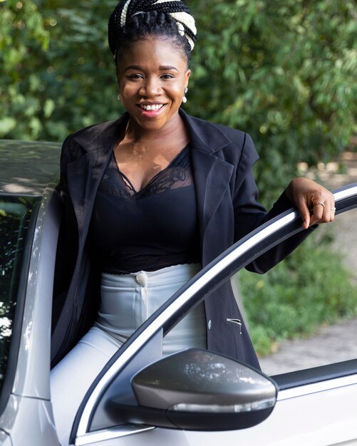 Vue de face de la femme souriante posant avec sa porte de voiture ouverte