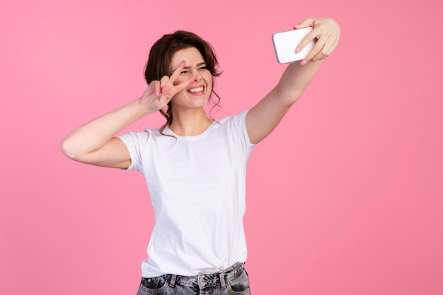 Photo gratuite vue de face d'une femme souriante prenant un selfie et faisant signe de paix