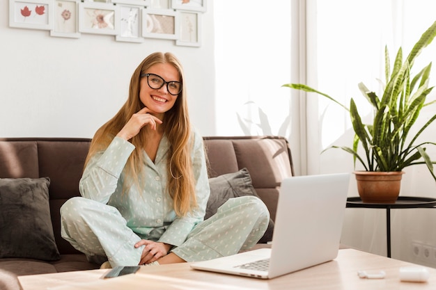 Vue de face de femme souriante en pyjama travaillant à la maison