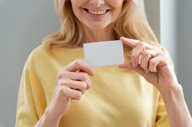 Vue de face femme souriante tenant une carte de visite