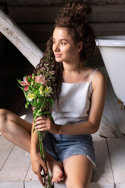 Vue de face femme souriante tenant des fleurs