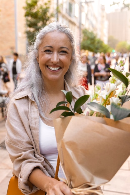 Vue de face femme souriante tenant des fleurs