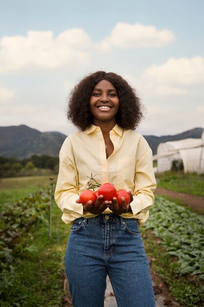 Vue de face femme souriante tenant des tomates