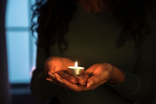 Vue de face femme tenant une bougie à la maison